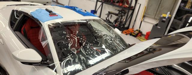 Clear film being installed on a white Lamborghini windshield